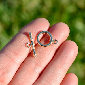 May include: Gold-toned metal clasp with a round ring and a toggle bar. The clasp is designed for jewelry making.