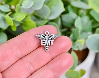 May include: Silver charm with a medical caduceus symbol and the letters "EMT" on it.