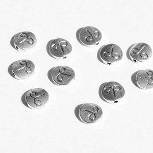 May include: A collection of silver-toned metal beads with the astrological symbol for Aries engraved on each bead.