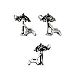 May include: Three silver charm pendants featuring a beach chair and umbrella. The charms are detailed with a textured finish and have a loop for attaching to a bracelet or necklace.