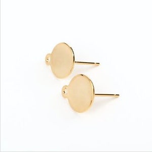 May include: A pair of gold-toned earring posts with round, flat discs attached. The discs have a small loop at the top.