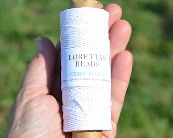 May include: A white spool of hemp cord with a label that reads "Loretta's Beads Hemp Spool 50grams | 20lb test (1mm) Approx. 205 feet"