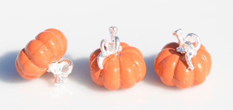 May include: Three small orange pumpkin charms with silver stems and leaves. The charms are perfect for adding a touch of fall to jewelry or crafts.