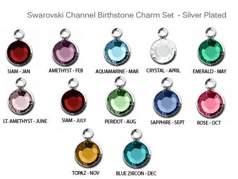 May include: A set of 12 silver-plated charms featuring Swarovski crystals in various colors, representing the birthstones for each month of the year. The charms are labeled with the month and birthstone name.