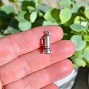 May include: Silver charm in the shape of a blender. The charm is small and detailed, with a silver finish.