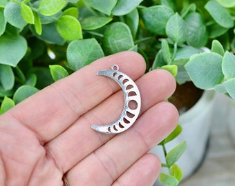 May include: Silver crescent moon charm with cut-out phases of the moon. The charm has a loop at the top for attaching to jewelry.