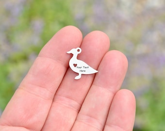 May include: Silver metal charm shaped like a duck with a heart cutout and the text "Your Text Here" engraved on the charm.