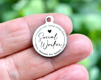 Könnte beinhalten: Ein runder silberfarbener Metallanhänger mit der eingravierten Aufschrift Social Worker in Schreibschrift. Über dem Text befindet sich ein kleines schwarzes Herz, umgeben von den Wörtern Compassionate, Caring, Loving, Kind, Warm, Dedicated, Fun, Reliable, Loyal.