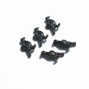 May include: Five black plastic buttons shaped like birds. The buttons have a textured surface and are designed to look like a bird in flight.