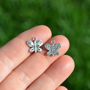 May include: Two silver butterfly charms. One charm is plain and the other charm has the words "Created For You" engraved on it.