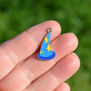 May include: A blue and yellow enamel charm shaped like a wizard's hat. The hat has a pointed top and a brim with a star design.
