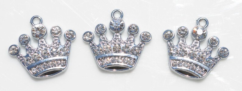 May include: Three silver crown charms with clear rhinestone accents.