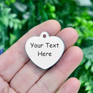 May include: A silver heart-shaped tag with the text "Your Text Here" printed on it.