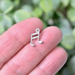 May include: Silver music note charm pendant. The note is a treble clef with a single line through the stem.