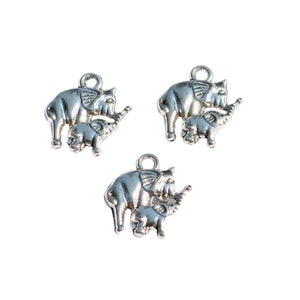 May include: Three silver charm pendants shaped like elephants with their babies. The elephants are standing with their trunks raised and their babies are standing next to them.