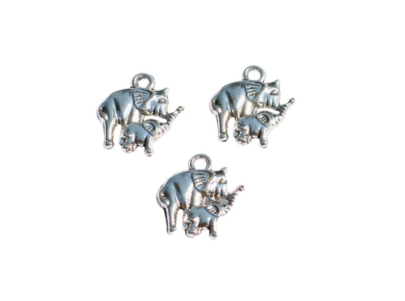 May include: Three silver charm pendants shaped like elephants with their babies. The elephants are standing with their trunks raised and their babies are standing next to them.
