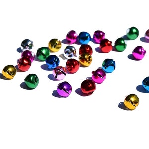 May include: A scattering of colorful jingle bells in various shades of red, green, blue, gold, pink, and purple. The bells are made of metal and have a shiny finish.