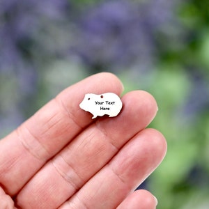 May include: A silver charm shaped like a guinea pig with a hole for a chain. The charm has the text "Your Text Here" engraved on it.