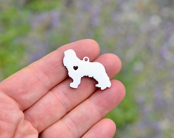 May include: Silver charm in the shape of a Newfoundland dog with a small heart cut out of the center. The charm is being held in a hand.