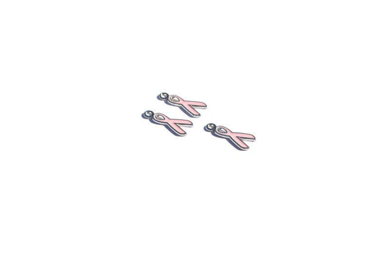 May include: Four pink ribbon charms with silver accents. The charms are designed to be used for jewelry making or other craft projects.