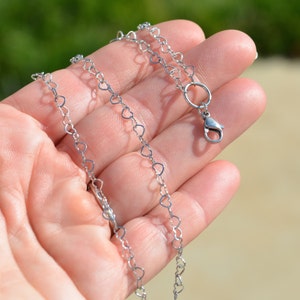 May include: A silver heart-shaped chain necklace with a lobster clasp closure.