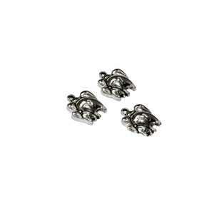 May include: Three silver turtle charms with a detailed design. The charms are small and perfect for adding a touch of whimsy to jewelry or crafts.