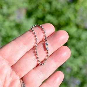 May include: A silver key chain with a ball chain and a silver clasp.