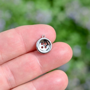 May include: A silver charm in the shape of a four-hole button.
