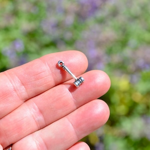 May include: A silver charm in the shape of a gavel, a small hammer used in legal proceedings.