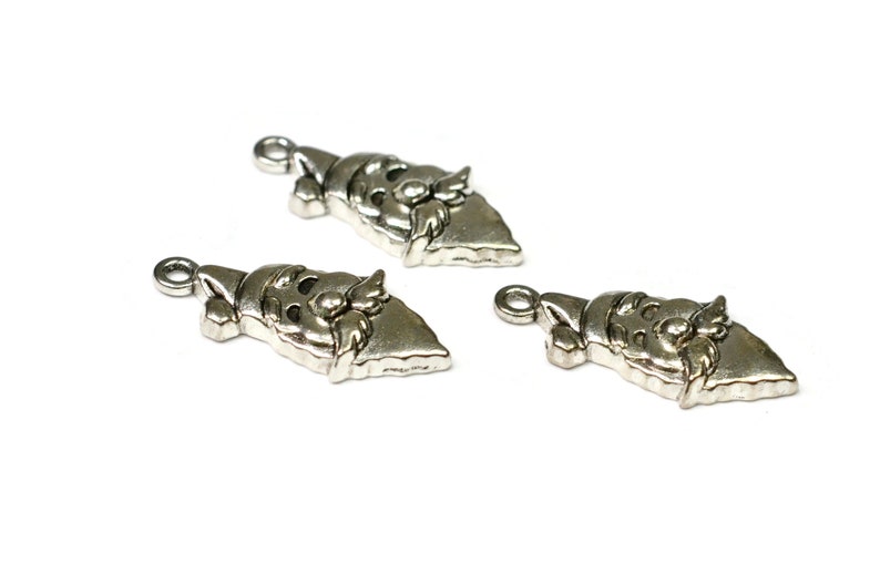 May include: Three silver-toned metal charms shaped like Santa Claus's face. Each charm has a loop at the top for attaching to a necklace, bracelet, or other jewelry.