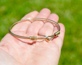 May include: A gold-toned wire bracelet with a hook clasp.