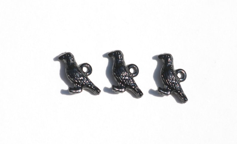 May include: Three black metal crow buttons with a loop for sewing on. The crows are in a standing position with their wings slightly spread.