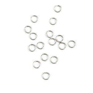 May include: A scattering of silver jump rings on a white background. The rings are small and circular, and they are arranged in a random pattern.