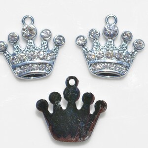May include: Three silver crown charms, two with clear rhinestones and one plain. The charms are perfect for jewelry making or adding a touch of sparkle to crafts.
