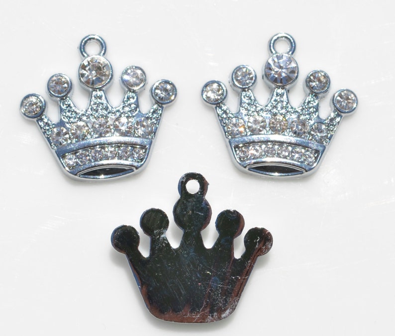 May include: Three silver crown charms, two with clear rhinestones and one plain. The charms are perfect for jewelry making or adding a touch of sparkle to crafts.
