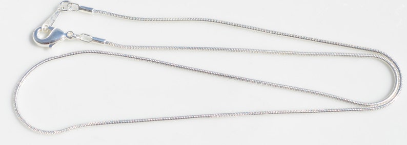 Puede incluir: Un collar de cadena de serpiente de plata con cierre de langosta.