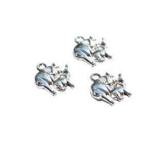 May include: Three silver charms in the shape of elephants. Each charm features a larger elephant carrying a smaller elephant on its back.