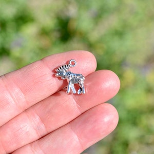 May include: Silver moose charm with a detailed design. The charm has a loop at the top for attaching to a necklace or bracelet.