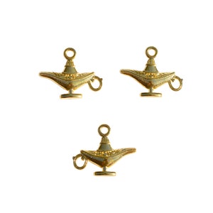 May include: Three gold-coloured genie lamp charms with a loop for hanging. The lamps are detailed with intricate designs.
