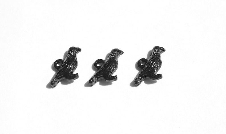 May include: Three black metal crow charms with a loop for attaching to a necklace, bracelet, or other jewellery.