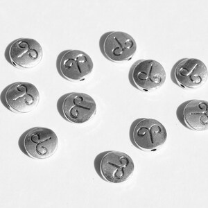 May include: A collection of silver-toned metal beads with the astrological symbol for Aries engraved on each bead.