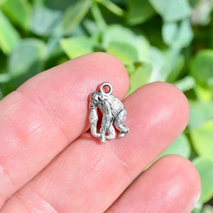 May include: Silver charm of a monkey with a detailed design. The charm has a loop at the top for attaching to a necklace or bracelet.