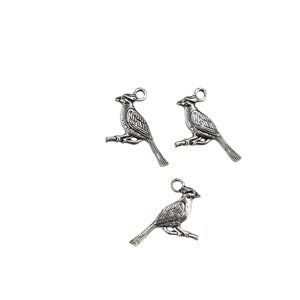 K&ouml;nnte beinhalten: Drei silberfarbene Vogel-Anh&auml;nger aus Metall mit einer &Ouml;se zum Aufh&auml;ngen. Die V&ouml;gel befinden sich in einer Sitzposition mit ausgebreiteten Fl&uuml;geln.