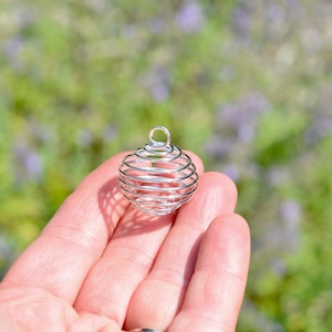 May include: A silver wire cage orb pendant, perfect for holding crystals or other small objects. The cage is made of thin wire and has a delicate, intricate design.