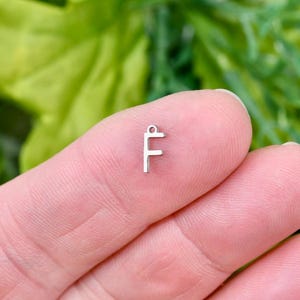 May include: Silver charm with the letter F, perfect for jewelry making or adding a personal touch to crafts.