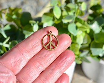 May include: A bronze peace sign charm pendant with a loop for attaching to a necklace or bracelet.