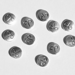 May include: Ten silver-colored metal beads with a raised Aries zodiac symbol on each bead.