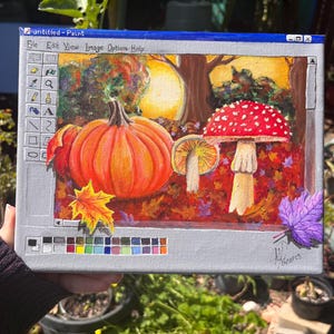 Może przedstawiać: Cyfrowy obraz przedstawiający jesienną scenę z dużą pomarańczową dynią, czerwono-białym grzybem i mniejszym grzybem z żółtym kapeluszem. Tło to las z jesiennymi liśćmi w odcieniach czerwieni, pomarańczy i żółci. Obraz jest oprawiony w niebiesko-szare okno, przypominające interfejs programu Microsoft Paint.