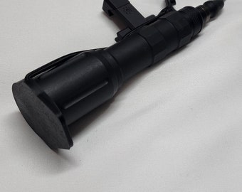 May include: A black tactical torch with a remote pressure switch. The torch has a textured grip and a black rubberised end cap. The remote switch is connected to the torch by a black wire.