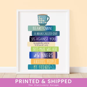 May include: A stack of books with the titles "Beartown", "A Man Called Ove", "Us Against You", "Britt-Marie Was Here", "The Winners", "Anxious People", and "My Friends". A blue coffee cup with white hearts sits on top of the books.